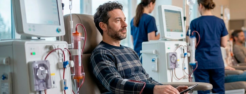 Un uomo seduto su una poltrona reclinabile mentre riceve un trattamento di emodialisi in un ospedale.