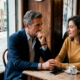 Uomo maturo pensieroso seduto al tavolo di un bar con una giovane donna che gli tiene la mano con affetto