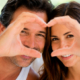 Coppia adulta sorridente forma un cuore con le mani davanti al viso