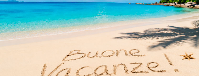 Spiaggia tropicale con mare cristallino, palme e scritta Buone Vacanze sulla sabbia